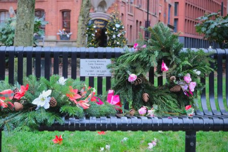Foto de Manchester, Reino Unido - 12 29 2023: Placa conmemorativa en honor a Colin Timmins llamada "Nana", famosa drag queen de Canal Street. El banco, en Sackville Gardens, está decorado con flores. - Imagen libre de derechos