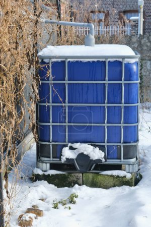 Rainwater collection tank, with blue walls, in a snowy setting.
