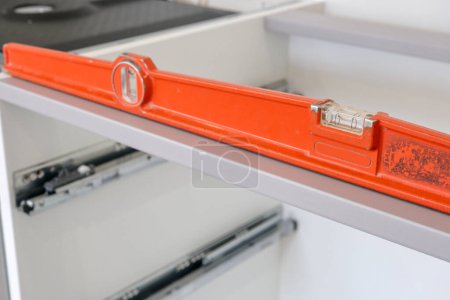 Photo for Orange level, placed on the structure of a kitchen base unit, to check its horizontality - Royalty Free Image