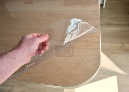 Protective tablecloth in transparent plastic, on a plywood kitchen table.