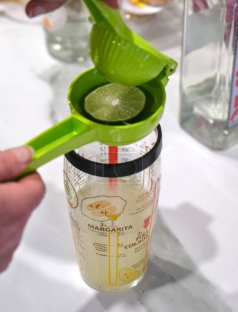 Photo for Citrus press squeezing a lime over a measuring glass - Royalty Free Image