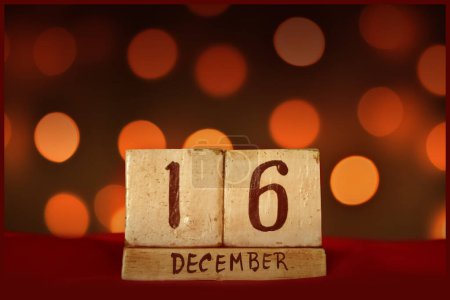 Photo for December 16 vintage wooden block calendar on red fabric, festive bokeh lights background greeting card celebrating holidays, birthday, save the date for special occasion. - Royalty Free Image