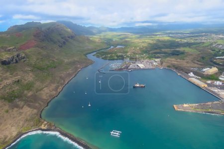 Vista aérea desde un helicóptero, bahía azul con barcos rodeados de montañas, prados verdes, Lihue, Kauai, Hawai