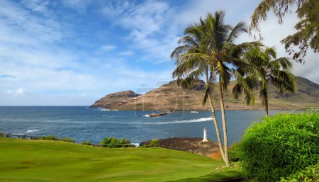 Téléchargez les photos : Paysage panoramique du phare de Kukii Point avec palmiers, mer bleue et ciel, parcours de golf vert et montagnes en arrière-plan, Kalapaki, Kauai, Hawaï, États-Unis - en image libre de droit