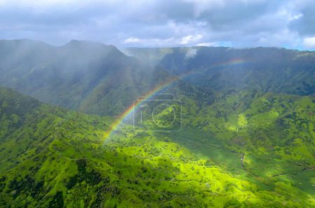 Regenbogen über grünem Tal und Bergen, Panoramaaufnahme aus einem Hubschrauber im Na Pali Coast State Wilderness Park, Kauai, Hawaii, USA