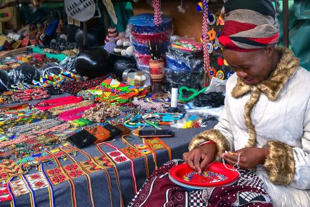 Photo for African woman making a necklace with colorful beads and selling souvenirs, handicraft at Manzini market, Eswatini, Swaziland, Africa - Royalty Free Image