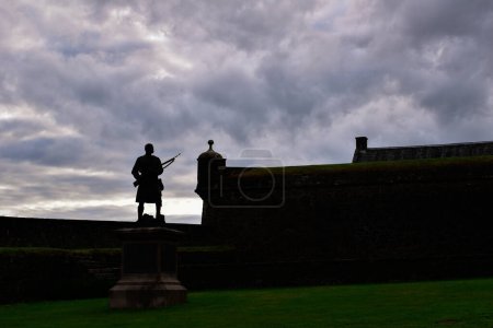 Photo for Silhouette of an armed kilt wearing Scotsman. Statue of sentry standing guard outside castle wall at Stirling, Scotland, United Kingdom, Europe. - Royalty Free Image