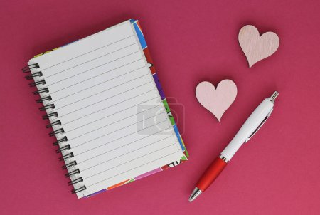 Téléchargez les photos : Carnet avec une feuille vierge pour écrire du texte avec un stylo et des décorations de coeur - en image libre de droit