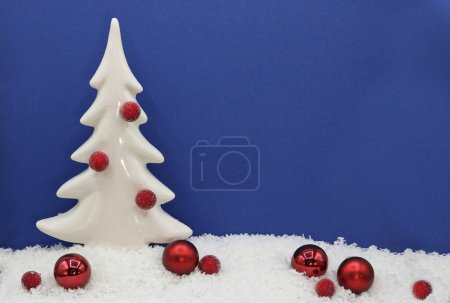 Weihnachtskarte mit einem weißen Baum in einer verschneiten Landschaft mit einer Weihnachtsdekoration aus roten Kugeln