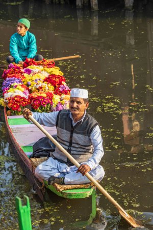 Téléchargez les photos : Rainawari, Srinagar, Jammu-et-Cachemire, Inde. 25 octobre 2022. Père et fils livrant des fleurs au marché dans un bateau shikara traditionnel au lac Dal. - en image libre de droit