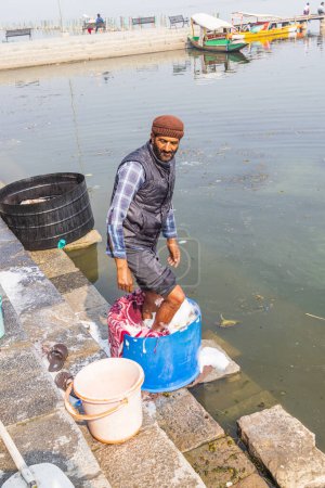 Téléchargez les photos : Hazratbal, Srinagar, Jammu-et-Cachemire, Inde. 30 octobre 2022. Homme lavant la lessive sur la rive du lac Dal. - en image libre de droit