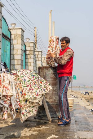 Téléchargez les photos : Hazratbal, Srinagar, Jammu-et-Cachemire, Inde. 30 octobre 2022. Homme lavant la lessive sur la rive du lac Dal. - en image libre de droit