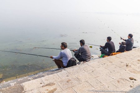 Téléchargez les photos : Hazratbal, Srinagar, Jammu-et-Cachemire, Inde. 30 octobre 2022. Hommes pêchant sur la rive du lac Dal. - en image libre de droit