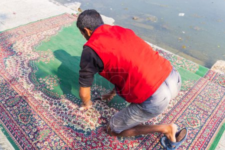 Téléchargez les photos : Hazratbal, Srinagar, Jammu-et-Cachemire, Inde. 30 octobre 2022. Homme lavant un tapis sur la rive du lac Dal. - en image libre de droit