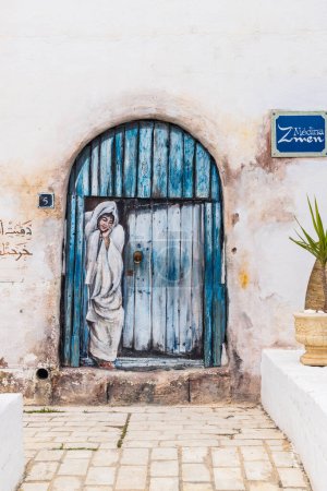 Téléchargez les photos : Yasmine Hammamet, Nabeul, Tunisie. Le 6 mars 2023. Peinture murale d'une femme à une porte à Yasmine Hammamet. - en image libre de droit