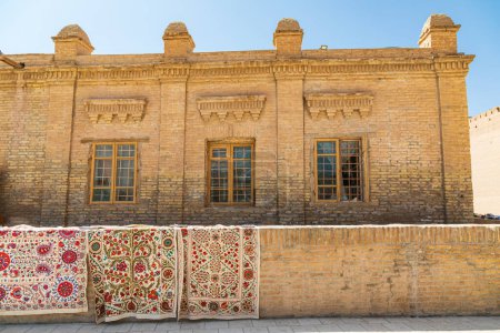 Khiva, Xorazm Region, Uzbekistan, Central Asia. Rugs displayed on a brick wall in Khiva.