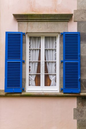 Furnas, Sao Miguel, Azoren, Portugal. Blaue Fensterläden an einem rosa stuckierten Gebäude.