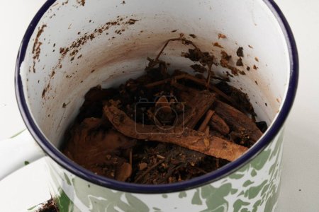 Ingrédients à base de plantes mijotant dans une tasse d'émail, brassée pour en extraire leur essence, connue sous le nom de "jamu", un remède naturel traditionnel.