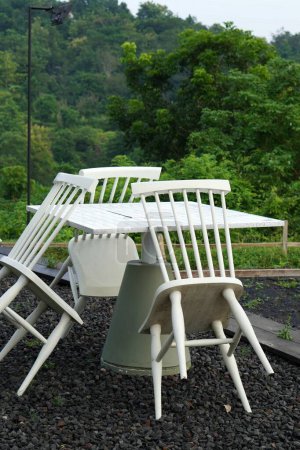 A white outdoor table with chairs leaned against it, set on gravel, signaling the cafe is not yet open.