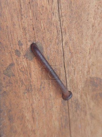 A rusty nail firmly embedded and bent in a piece of wood, telling tales of time and resilience.