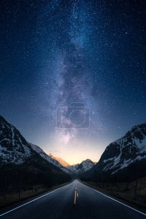 Photo for A road between mountains leading towards horizon with epic milky way on the sky - Royalty Free Image
