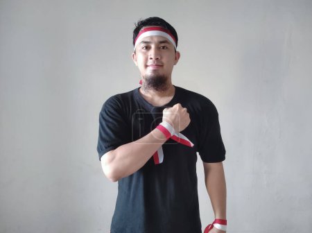 Téléchargez les photos : Homme indonésien portant un t-shirt noir et serrant son poing sur sa poitrine pendant la célébration de la fête de l'indépendance - en image libre de droit
