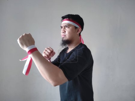 Téléchargez les photos : Homme indonésien portant un t-shirt noir et bandeau drapeau indonésien avec expression de colère - en image libre de droit