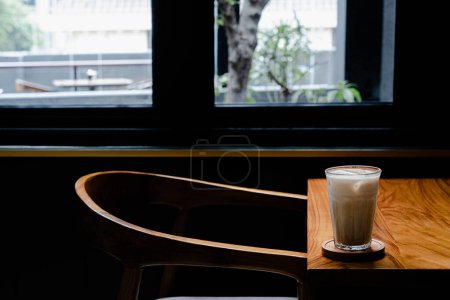 Photo for Hi-res photo of an empty chair with a glass of iced coffee latte in the wooden table, narrow depth of field or blurred background - Royalty Free Image