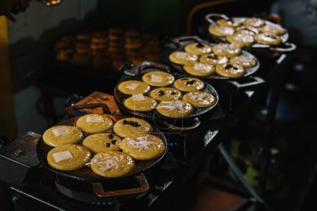 Foto de La leche de coco, la harina, los huevos y las papas se fríen en una sartén de pastel para producir aperitivos tradicionales indonesios conocidos como Kue Lumpur o Mud Cake. - Imagen libre de derechos