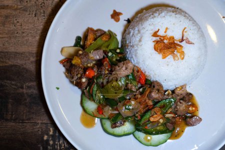 Foto de Stir-fried pork meat with Indonesian herbs and spices and white rice on a white plate. Flat lay or top view. - Imagen libre de derechos