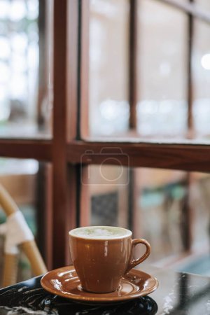 Foto de Retrato o plano vertical de una taza de Matcha Latte con Latte Art sobre una mesa de mármol negro cerca de la ventana. Fondo borroso. - Imagen libre de derechos