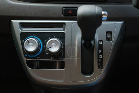 Air conditioner controls with knobs and automatic transmission handle on a car dashboard