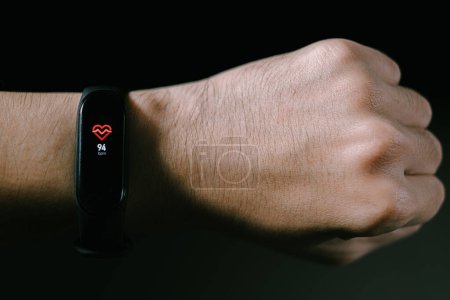 Téléchargez les photos : Une montre intelligente dans la main des hommes montre un rythme cardiaque. Fond noir isolé. - en image libre de droit
