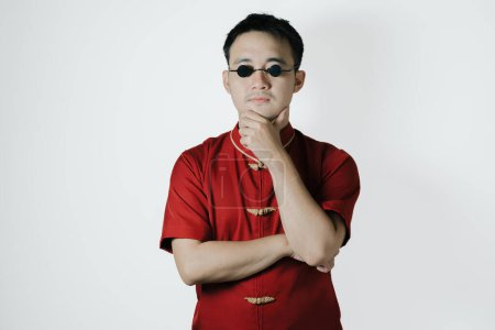 Confused face of Asian man wearing traditional costume on white background. Chinese New Year concept. Gong Xi Fa Cai.
