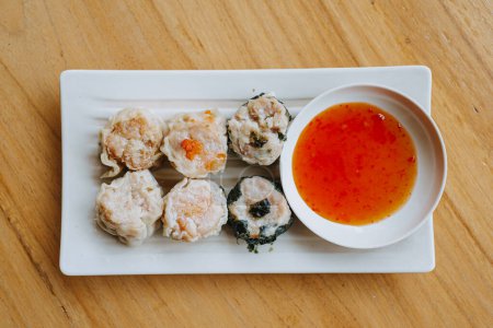 Photo for A plate of Dim Sum with chili sauce on wooden table. Flat lay or top view shot. - Royalty Free Image