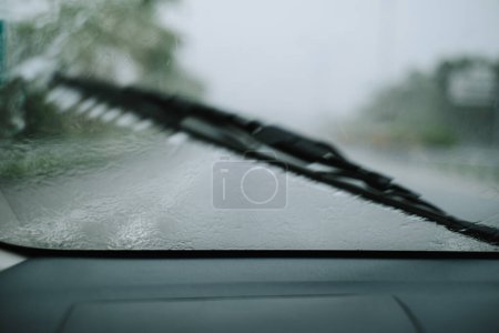 Photo for A wiper is cleaning the raindrops on the front glass of a car. Motion blur shot. - Royalty Free Image