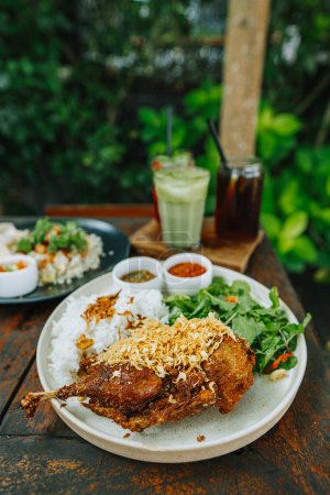 Indonesian Lunch Menu: Deep fried duck with rice and three types of cocktails. Food photography with bokeh background.