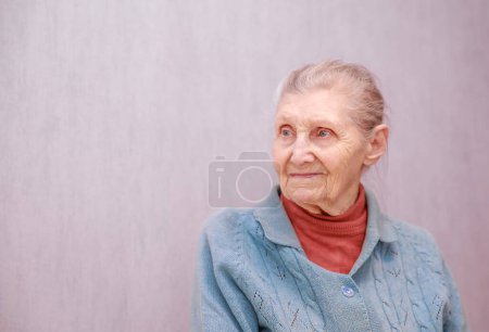 Portrait of an old woman, a grandmother sits in a chair, shot close-up, wrinkles on the old face, beautiful old age.
