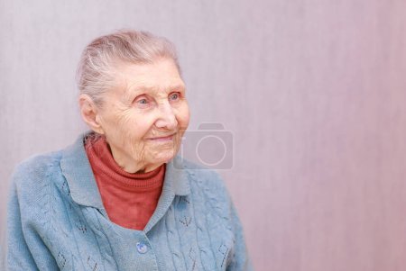 Portrait of an old woman, a grandmother sits in a chair, shot close-up, wrinkles on the old face, beautiful old age.