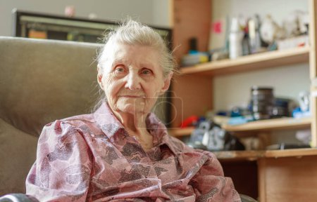 Portrait of a grandmother, an old woman with a wrinkled face sits in the room and smiles.