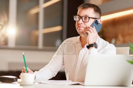 Businessman answering the phone sitting at office desk in front of laptop, easy internet banking, manager consulting customer by phonehaving successful mobile negotiations with client.