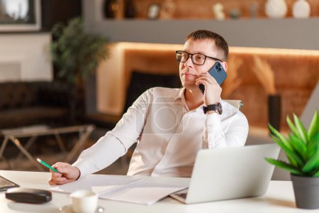 Businessman answering the phone sitting at office desk in front of laptop, easy internet banking, manager consulting customer by phonehaving successful mobile negotiations with client.