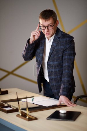 Portrait of a man in a suit. The man speaks on the phone. Important business negotiations. Office worker, sales manager, head of sales department. Serious man adjusts the sleeve of his jacket.