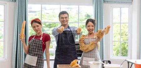 Téléchargez les photos : Partenariat d'affaires entre un homme et deux jeunes femmes dans une boulangerie maison. Formation boulangerie avec des jeunes filles dans une maison - en image libre de droit