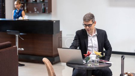 Photo for A male traveler enjoys using airline business lounge at a terminal waiting for departure. Business man uses computer laptop to check his travel plan and boarding in a lobby room. - Royalty Free Image