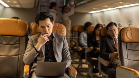 Photo for Young business man using computer notebook to connect and check his work in an airplane cabin before boarding. Traveler enjoys internet connection while taking a flight - Royalty Free Image