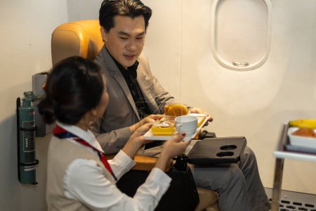 Stewardess oder Stewardess servieren ihrem männlichen Kunden während des Fluges Erfrischung und Schlange. Inflight Service für Business Class Passagiere