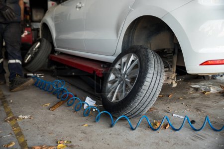 Téléchargez les photos : Mécanicien automobile avec tournevis électrique changer de pneu à l'extérieur. Service de voiture. Concept d'installation des pneus. Photo de haute qualité - en image libre de droit