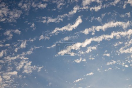 Téléchargez les photos : Blue sky background with clouds. Beautiful sunset sky above clouds with dramatic light. Fluffy clouds at sunset. High quality photo - en image libre de droit