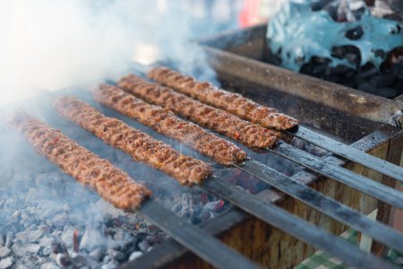 Téléchargez les photos : Délicieux barbecue kebab grill sur barbecue ouvert, cuisine extérieure. festival gastronomique en ville. savoureux rôtissage des aliments sur brochettes, food-court. pique-nique d'été. Photo de haute qualité - en image libre de droit